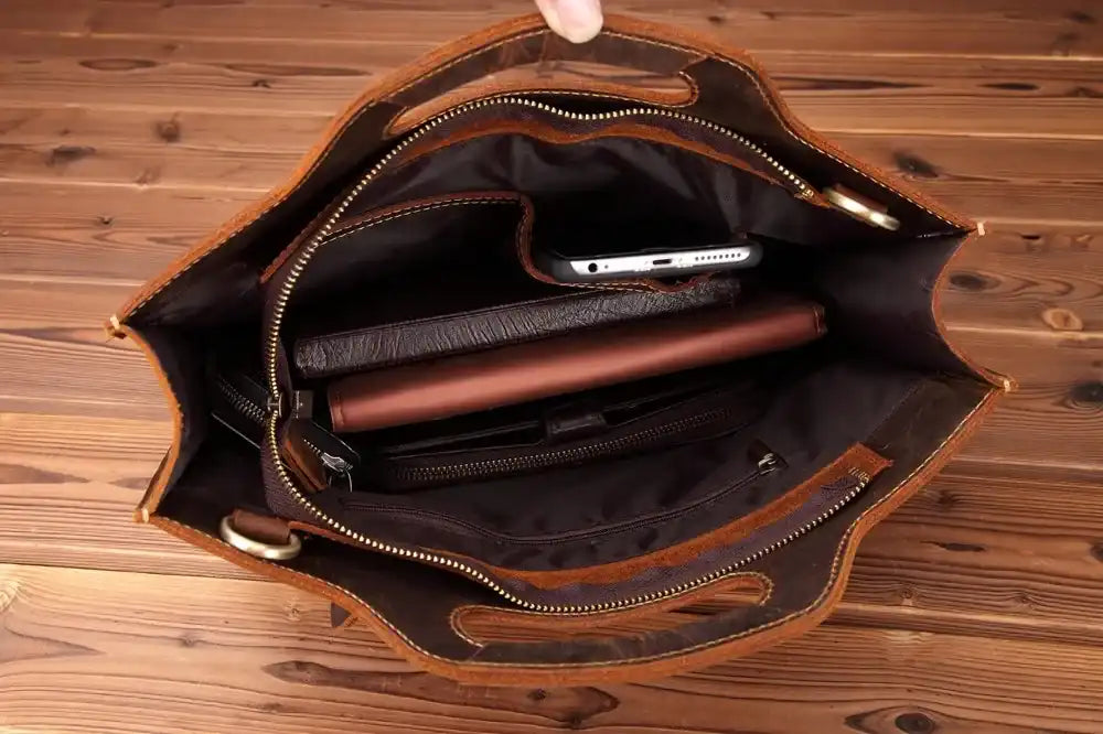 inside view of a leather bag, highlighting its interior compartments for phone, tablet and other personal items.
