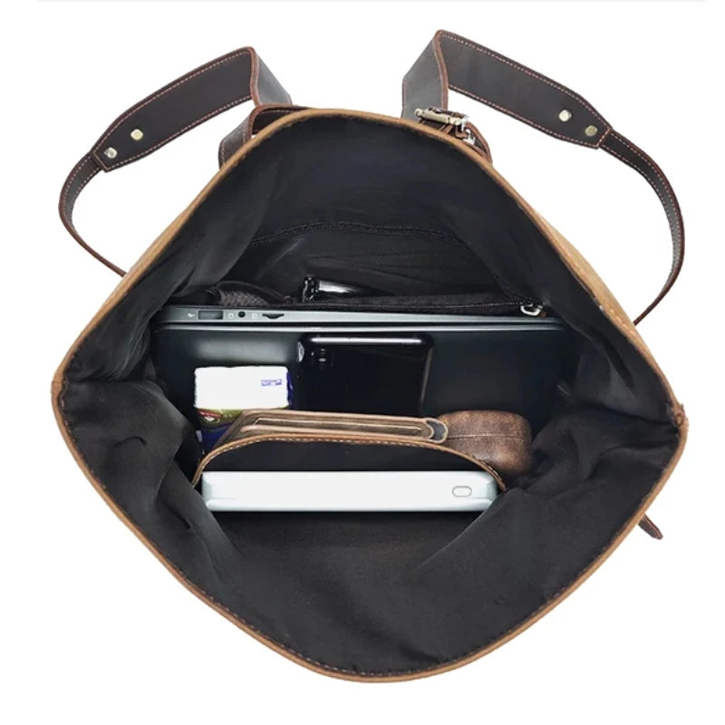interior view of a leather bag, showing a laptop, cell phone and wallet efficiently organized.