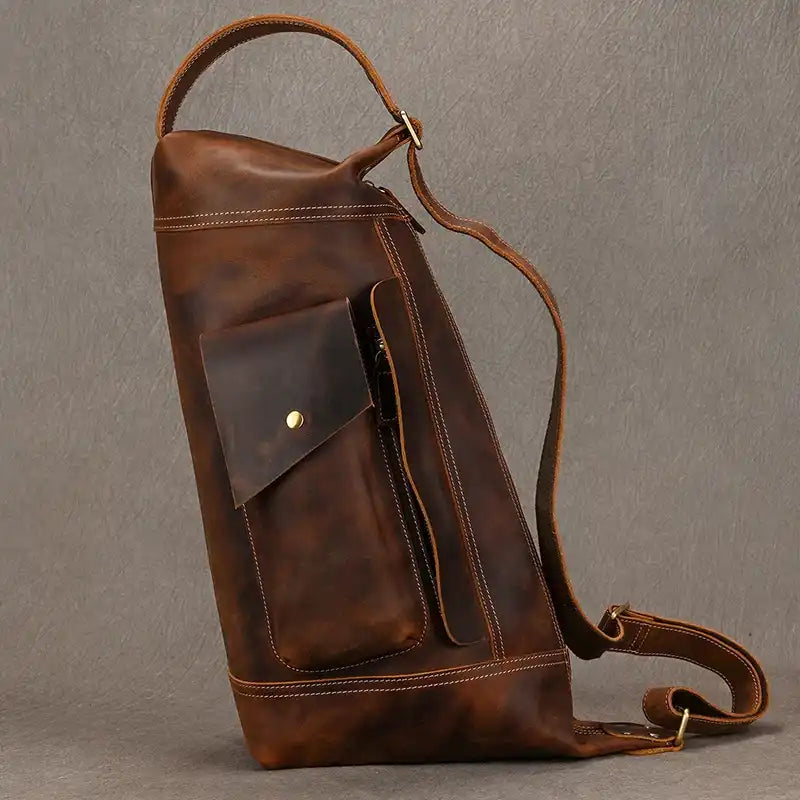 Side view of a large dark brown vintage leather bag with a pocket and zipper.