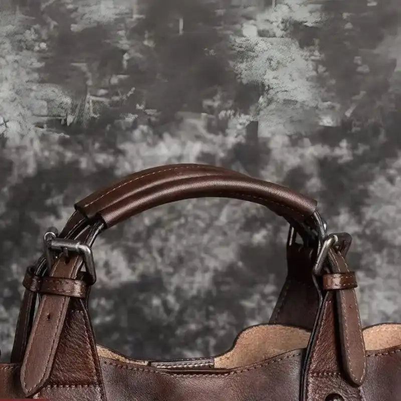 Detail of a brown leather bag with  handles, highlighting the finish and texture of the material.