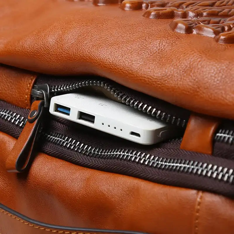 Close-up of a brown leather bag with a power bank peeking out of the zippered pocket.