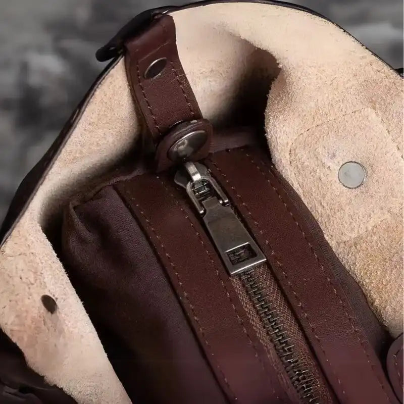 Interior detail of a leather bag, highlighting the zippers and soft fabric lining.