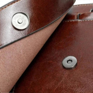 Close-up view of a brown leather bag showing the interior and snap button details.