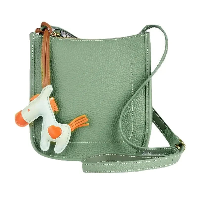 Stylish green leather crossbody bag with a playful horse charm - front view