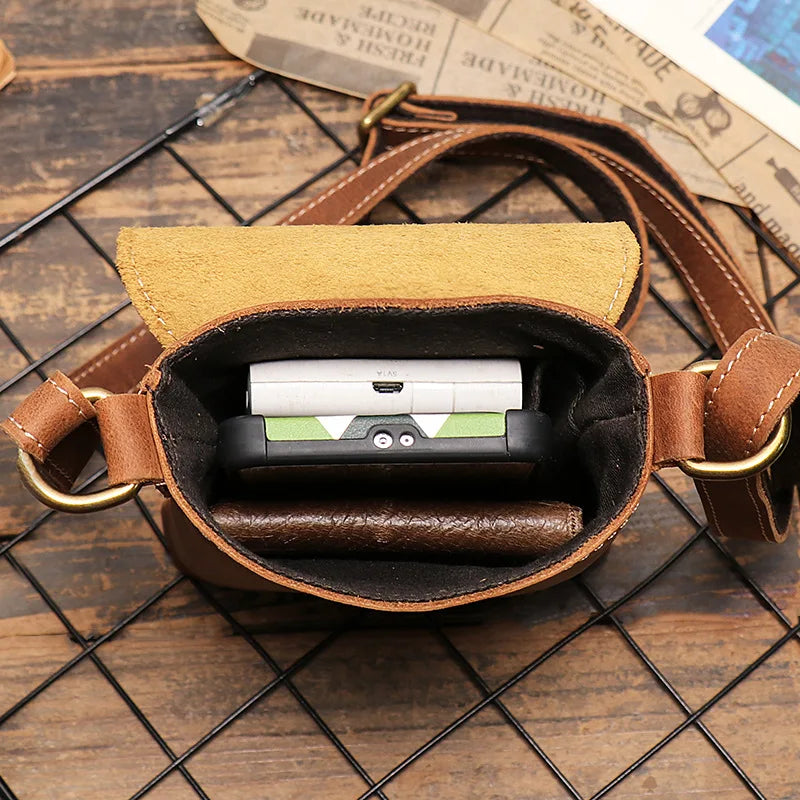 Inside view of a stylish brown leather mini shoulder bag with a phone and wallet.
