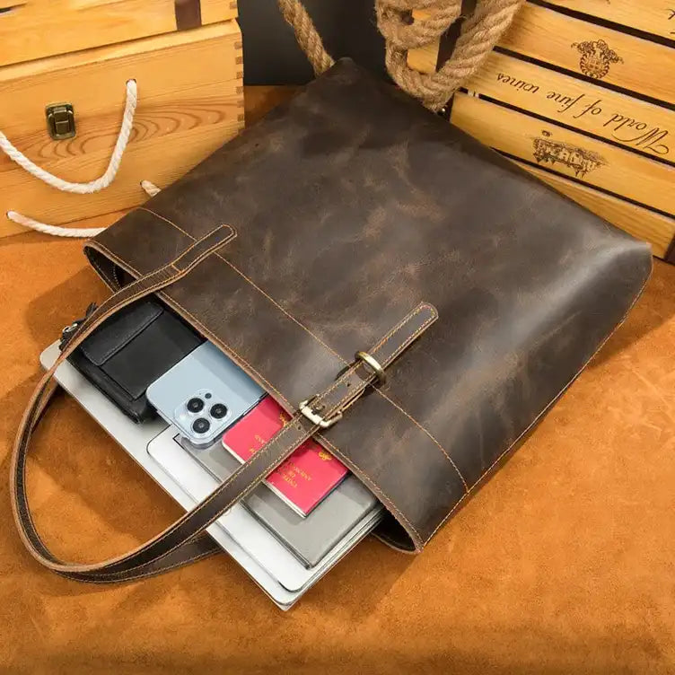 Stylish leather tote bag showcasing a laptop, phone, and wallet inside.