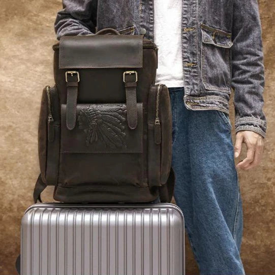 A stylish leather backpack resting on a silver travel suitcase.