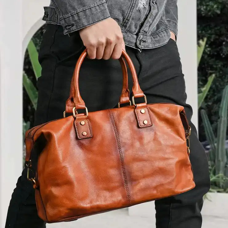 Man holding a brown leather bag in a modern setting. The bag is stylish and versatile, ideal for all occasions.