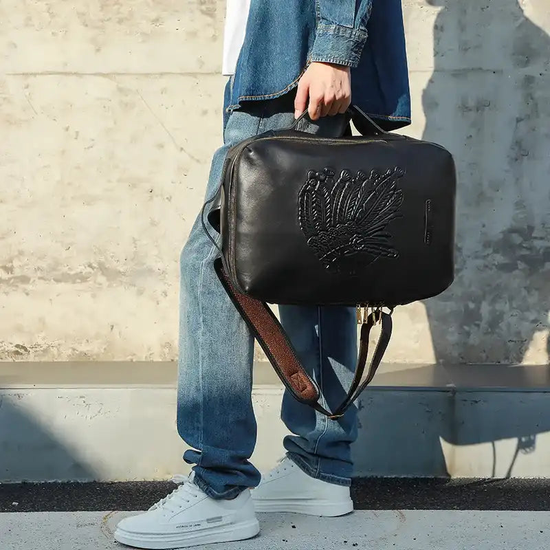A black leather backpack featuring a unique embossed design, held by a person in casual attire.