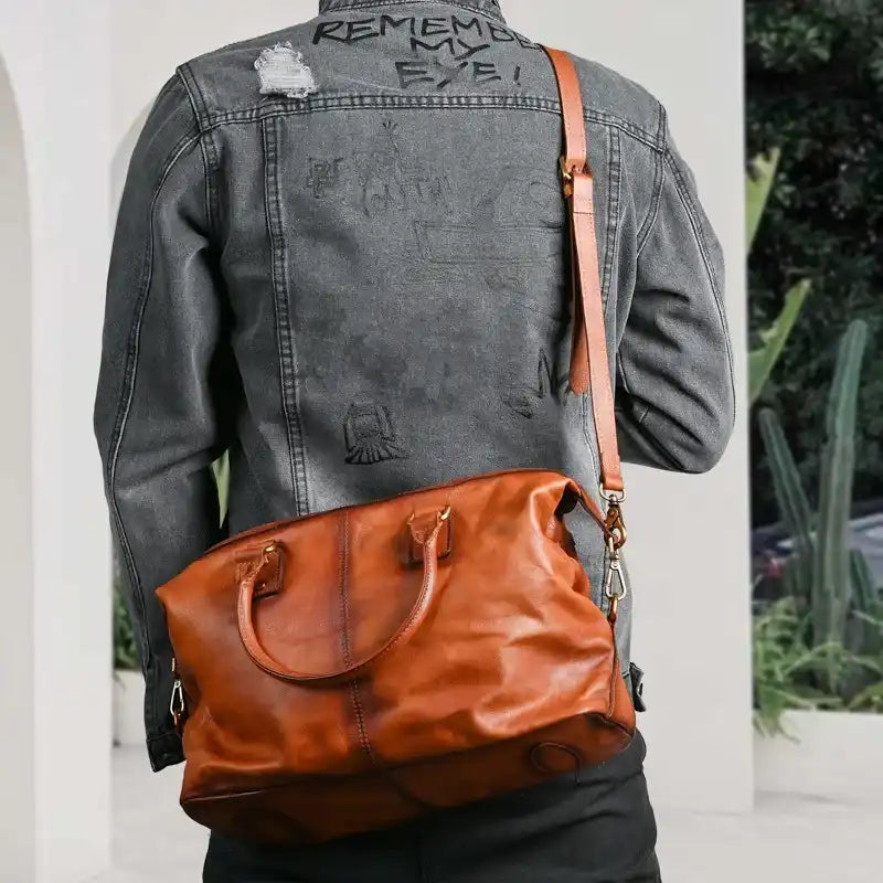 back view of a man wearing a dark denim jacket and a brown leather shoulder bag.