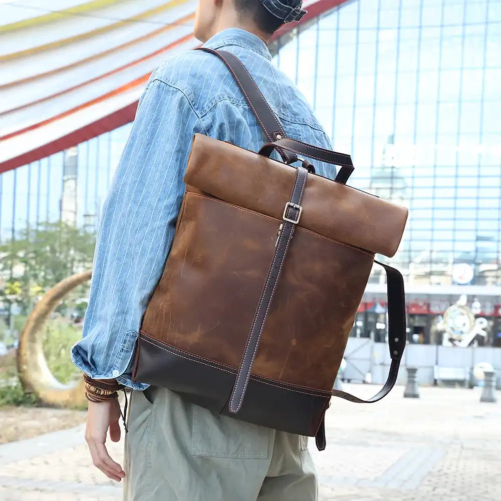 Stylish brown leather backpack, worn by a young man on the shoulder in an urban environment.