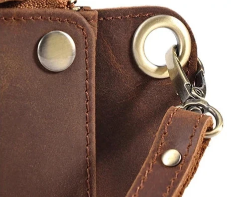 Detail of a metal clasp and button on a brown leather accessory.