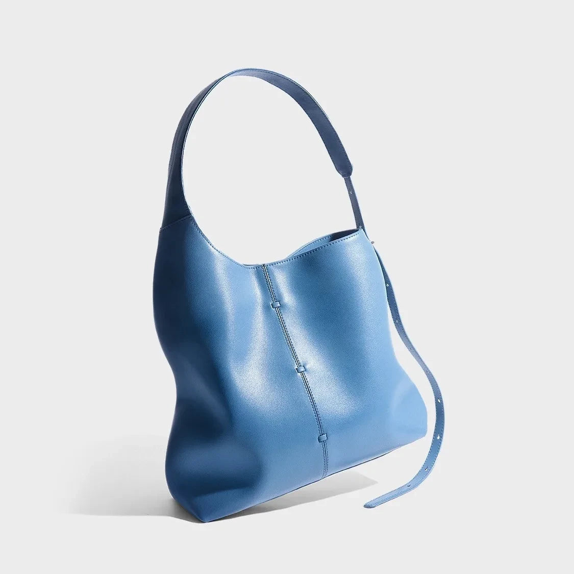 Elegant blue leather bag with a modern design and adjustable strap. 
