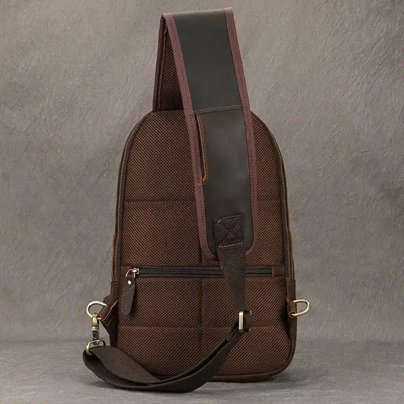  back view of a brown shoulder bag with a modern design, a wide strap and back zipper.