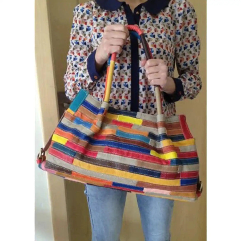 a colorful and stylish leather bag with several colorful stripes held by a modern woman.