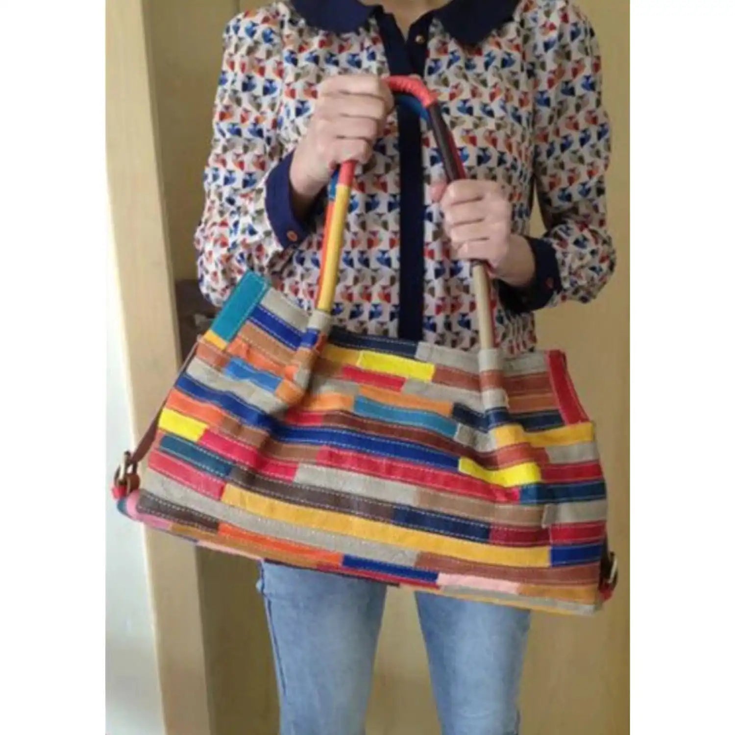 a colorful and stylish leather bag with several colorful stripes held by a modern woman.