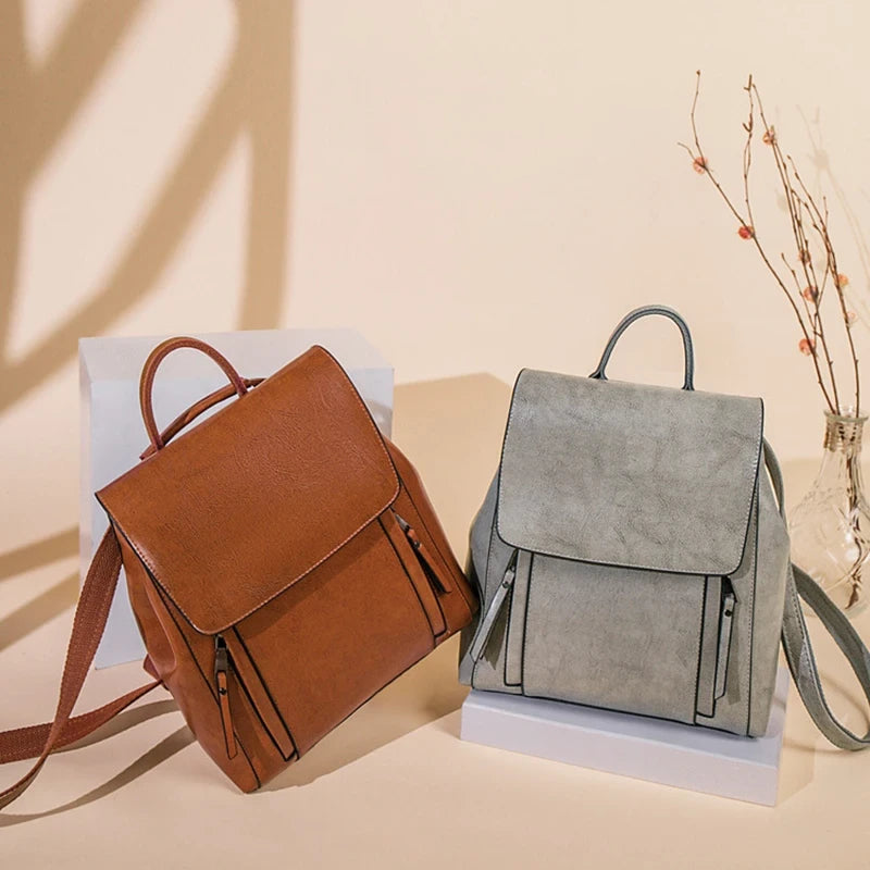 Two stylish leather backpacks in brown and grey displayed on a light background.
