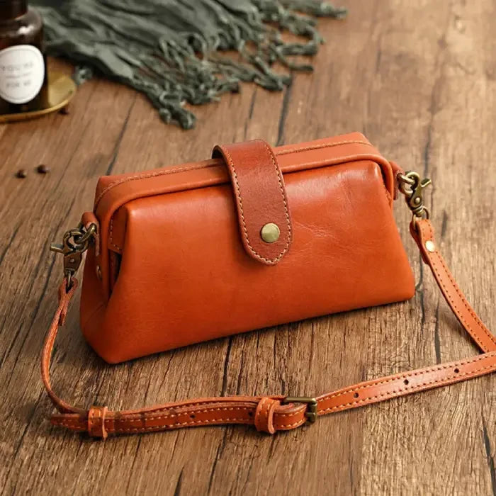 Orange leather shoulder bag with leather adjustable strap and snap closure, front view.