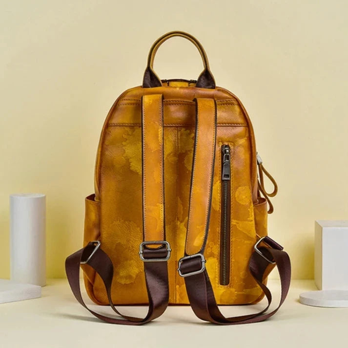 Orange leather backpack with floral details and adjustable straps, back view.