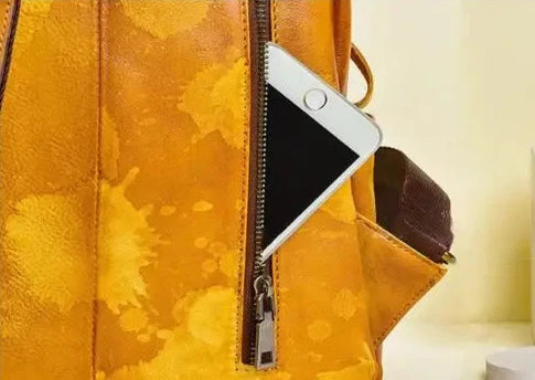 a black cell phone stored in an orange leather bag pocket, highlighting the functionality and style of the bag.