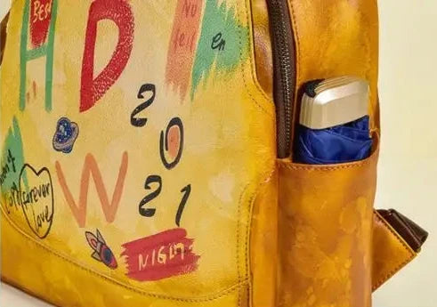 side pocket of a colorful leather bag in yellow tones with vibrant art and decorative words.