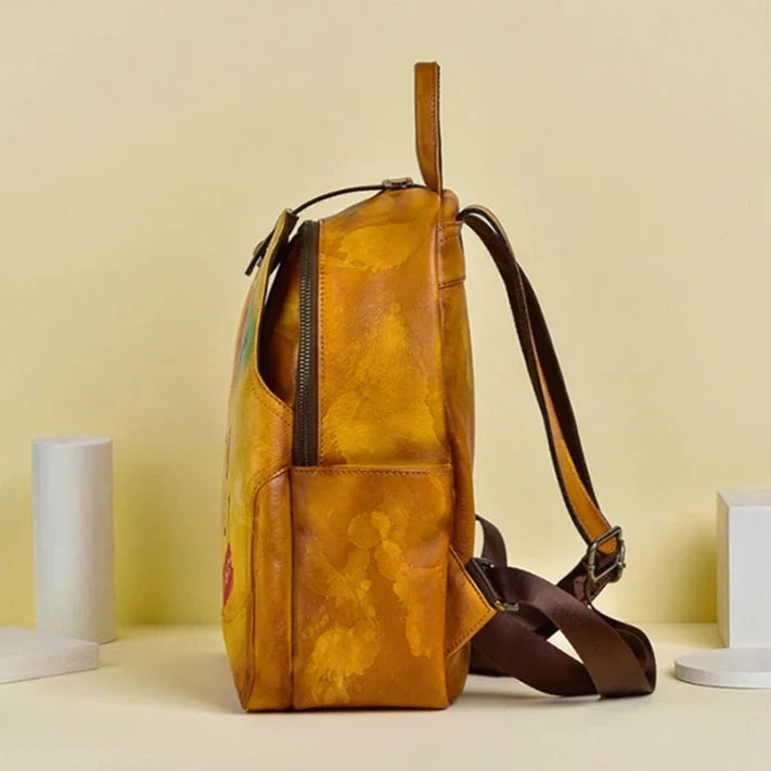 Orange leather backpack with artistic design, featuring brown straps and zipper closure, side view.