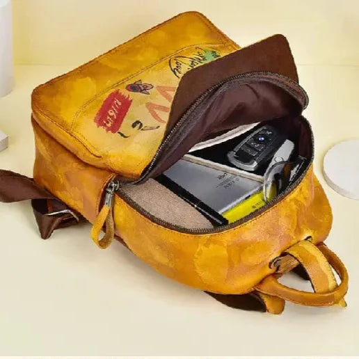 Stylish yellow backpack, open and displaying items such as a smartphone and notebooks.