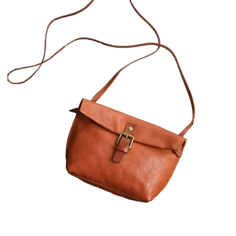 Brown leather handbag with a strap on a white background, front view.