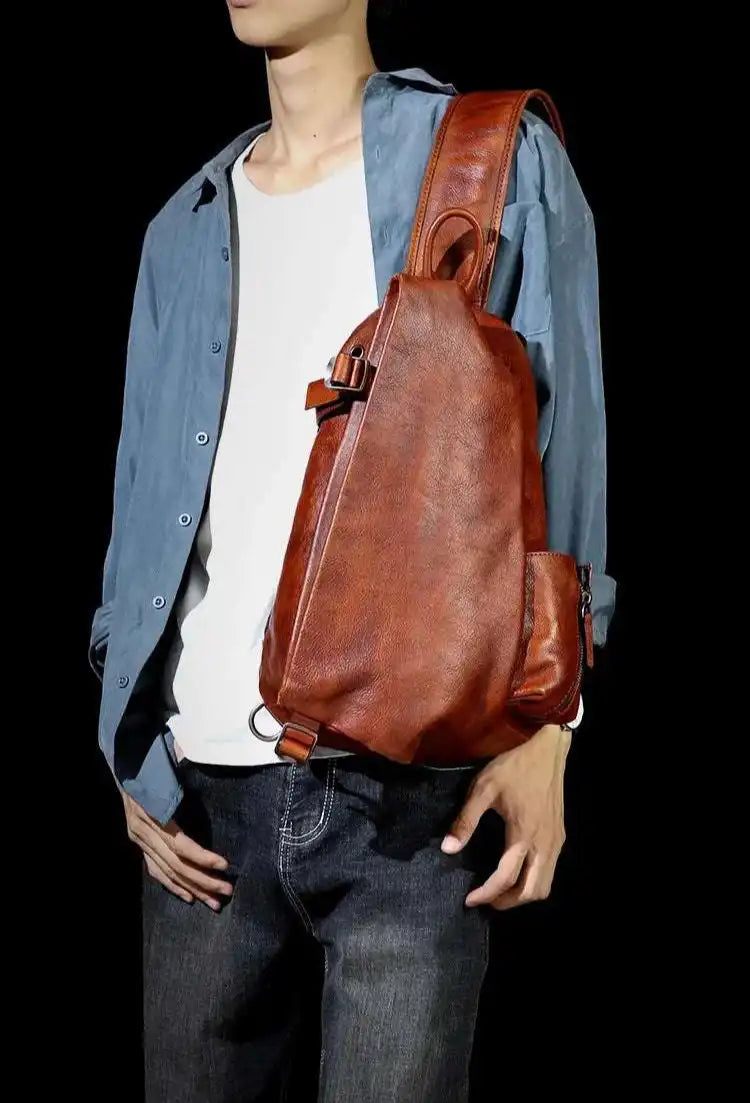 A brown leather shoulder bag with ergonomic design worn by a man on the shoulder.