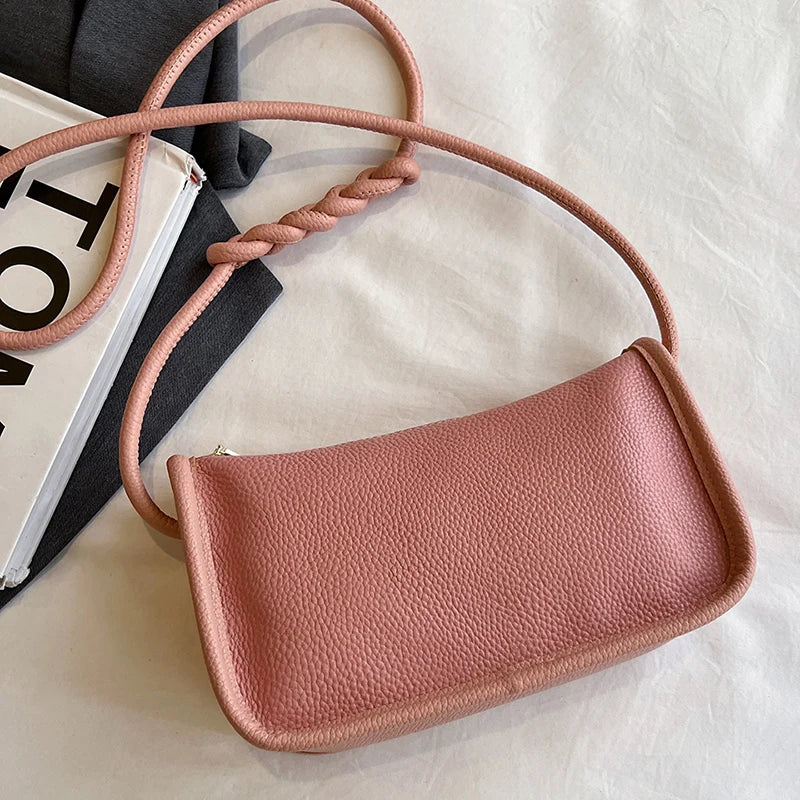 Stylish pink leather crossbody bag with braided strap.