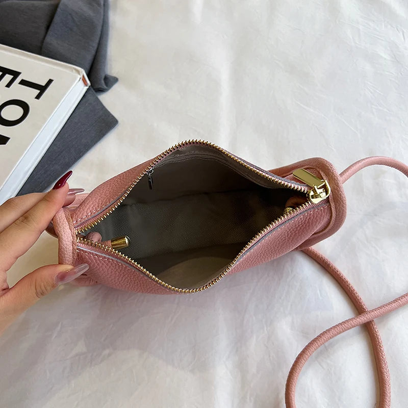 Trendy pink leather crossbody bag with an open zipper showing the spacious interior.