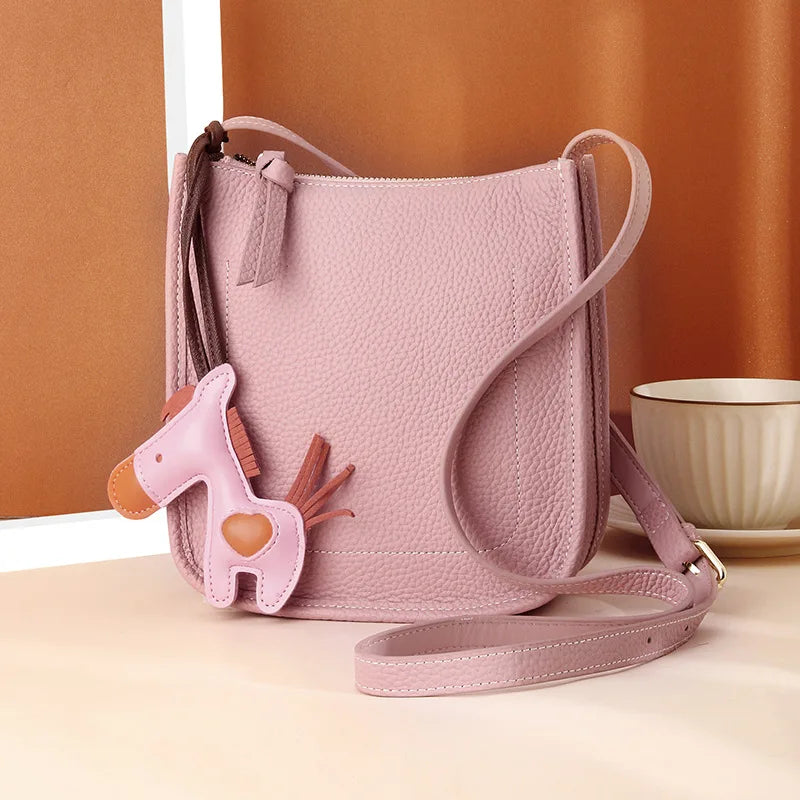 Front view of an elegant leather crossbody bag in pink with a playful horse charm for a unique touch.