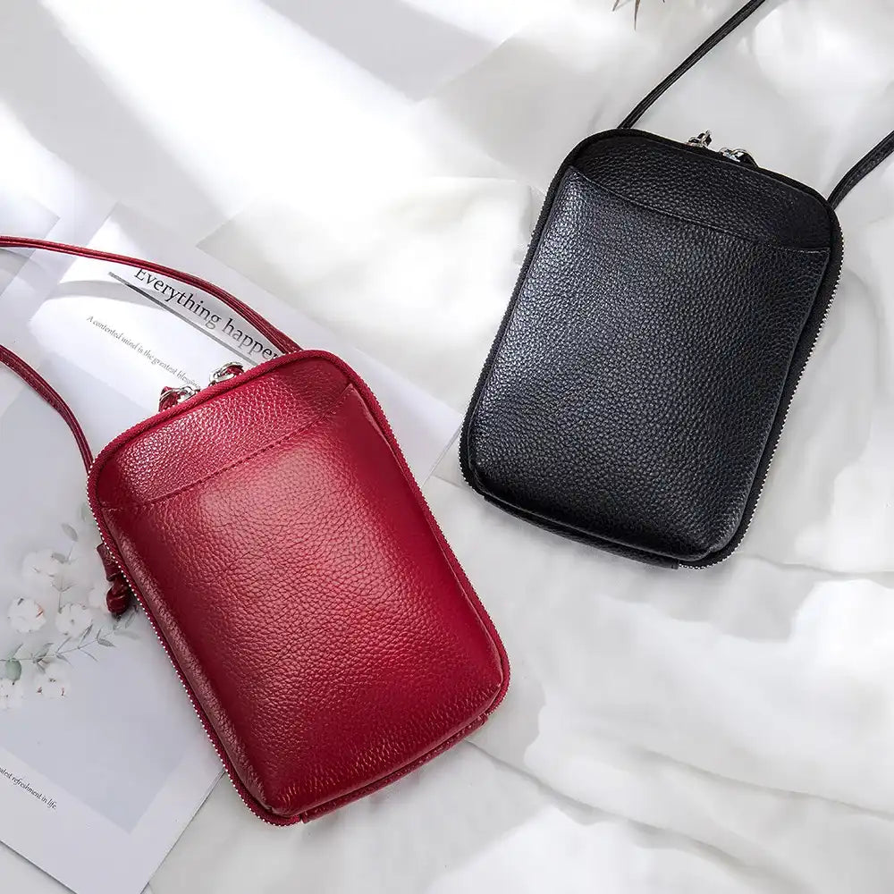 two leather crossbody bags, one in red and one in black, placed on a light surface - top view.
