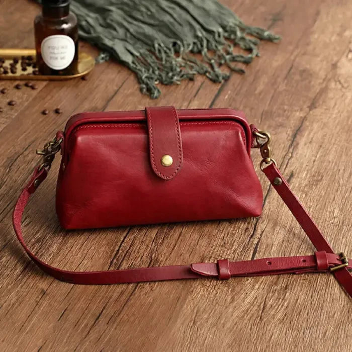 Red leather shoulder bag with leather adjustable strap and snap closure, front view.