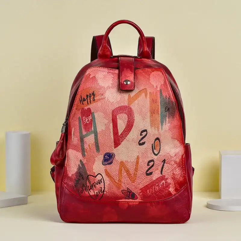 Red leather backpack with an artistic design filled with vibrant colors and drawings, front view.