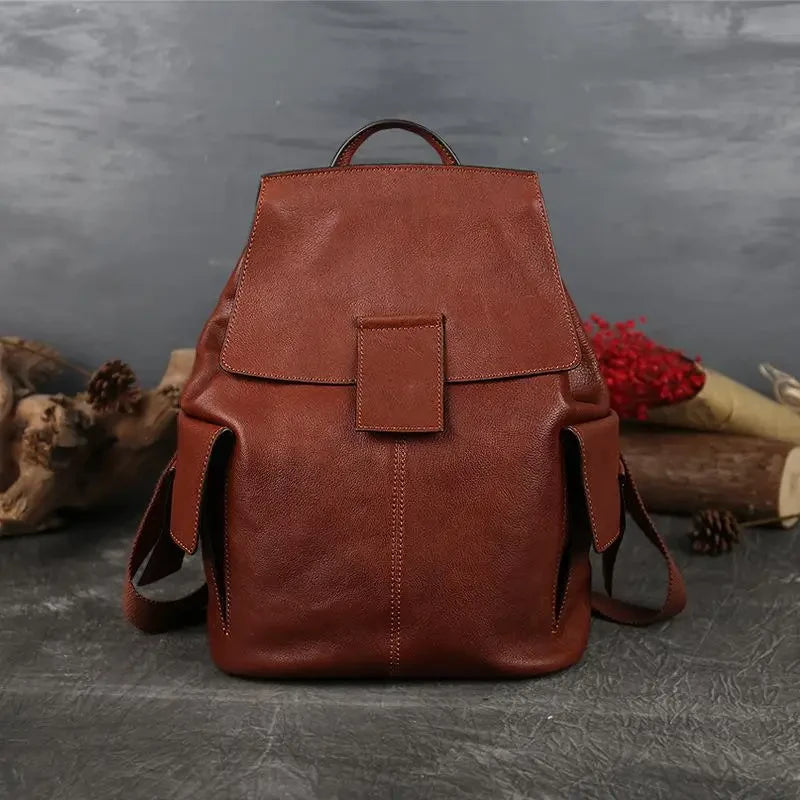 Stylish large red brown leather backpack with strap and handle in a minimalist design, front view.