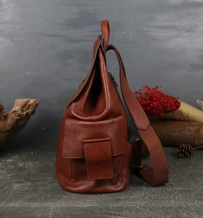 side view of a red brown leather bag with a modern design, with adjustable strap and side pocket.
