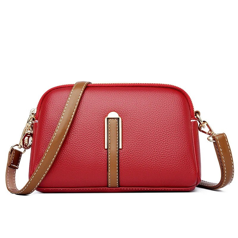 Chic red leather crossbody bag featuring a gold accent and a brown strap - front view.