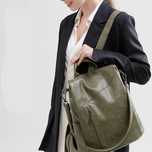 A stylish green leather bag being carried on the shoulder by a woman in a black blazer.