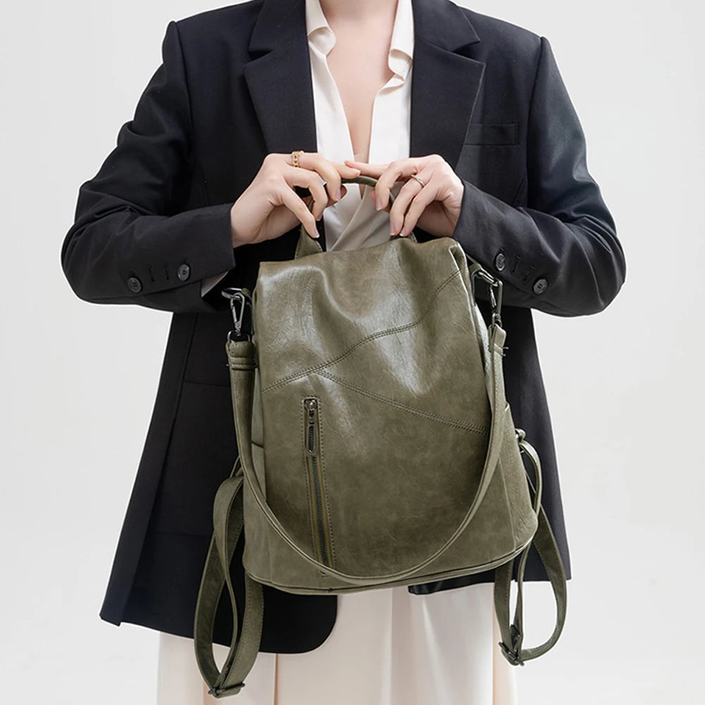 A fashionable green leather backpack held by a model in a black blazer.