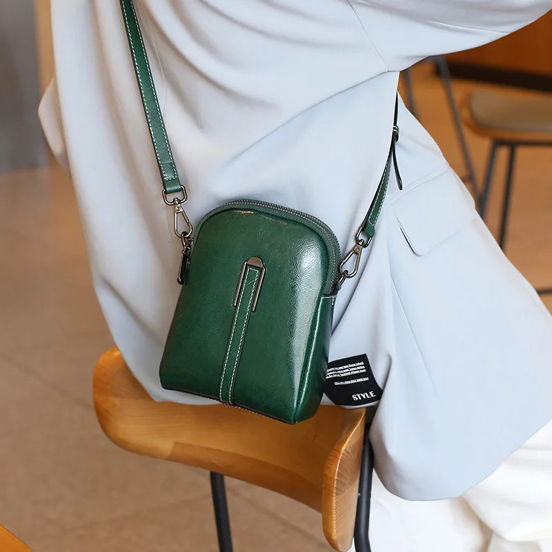 Trendy green leather crossbody bag in green color worn casually by modern woman.