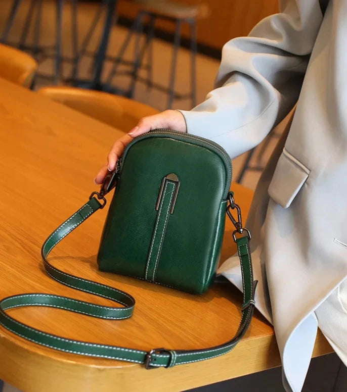 A trendy leather crossbody bag in green color, highlighting its stylish design and leather strap - front view