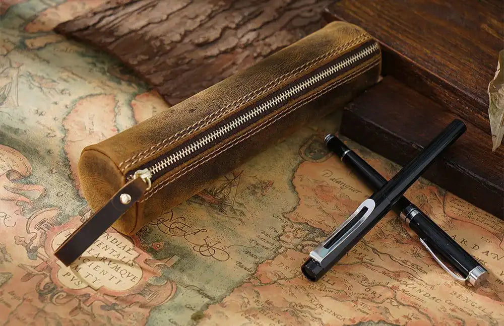 vintage brown leather pen case placed on a vintage map with pens.