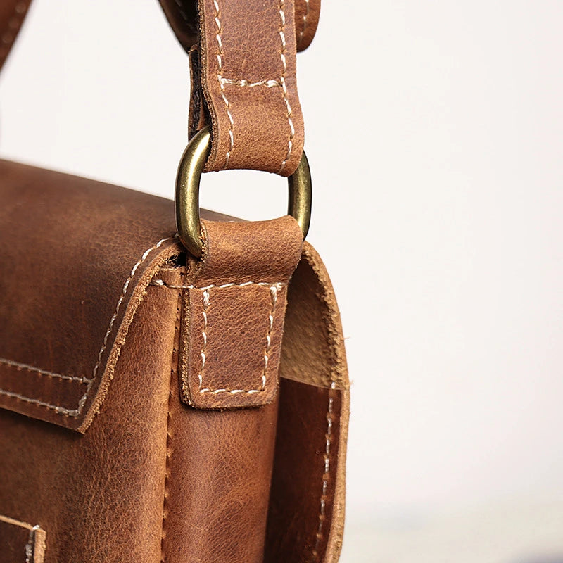 Close-up of a brown vintage leather bag showcasing its strap and stitching.