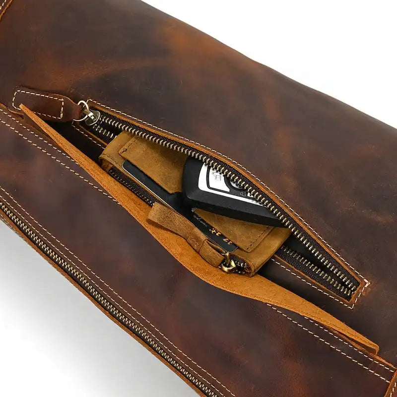 a dark brown leather bag with a zipper, showing the interior and organized objects.