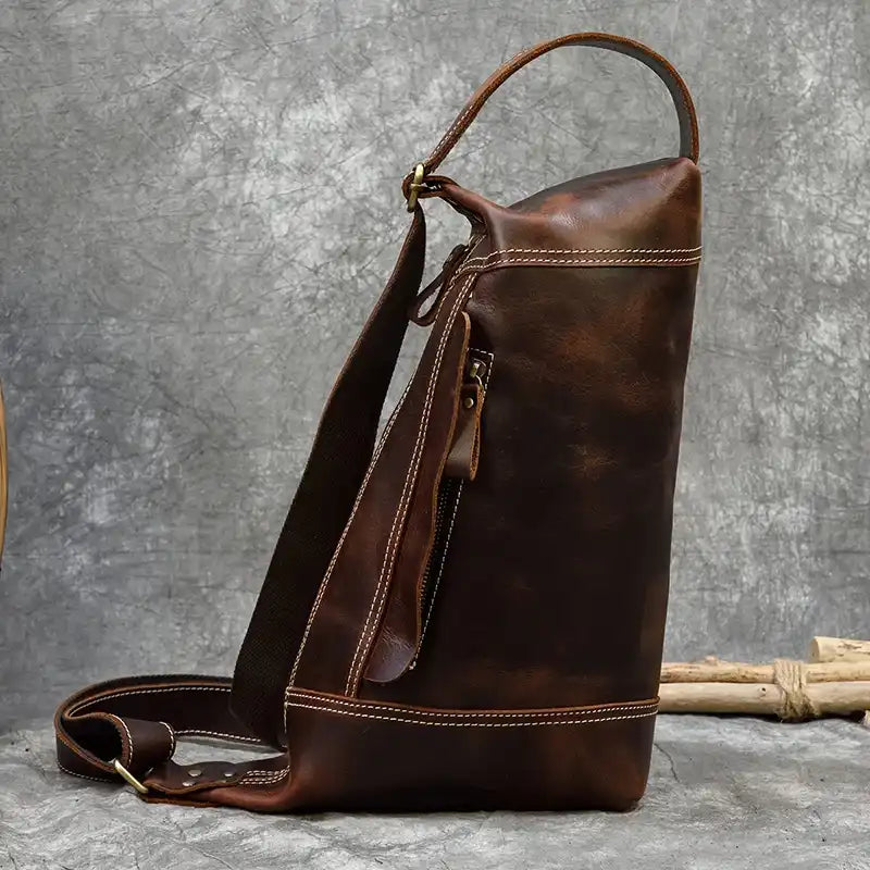 Side view of a brown leather bag with zipper pocket showcasing its craftsmanship and unique design.