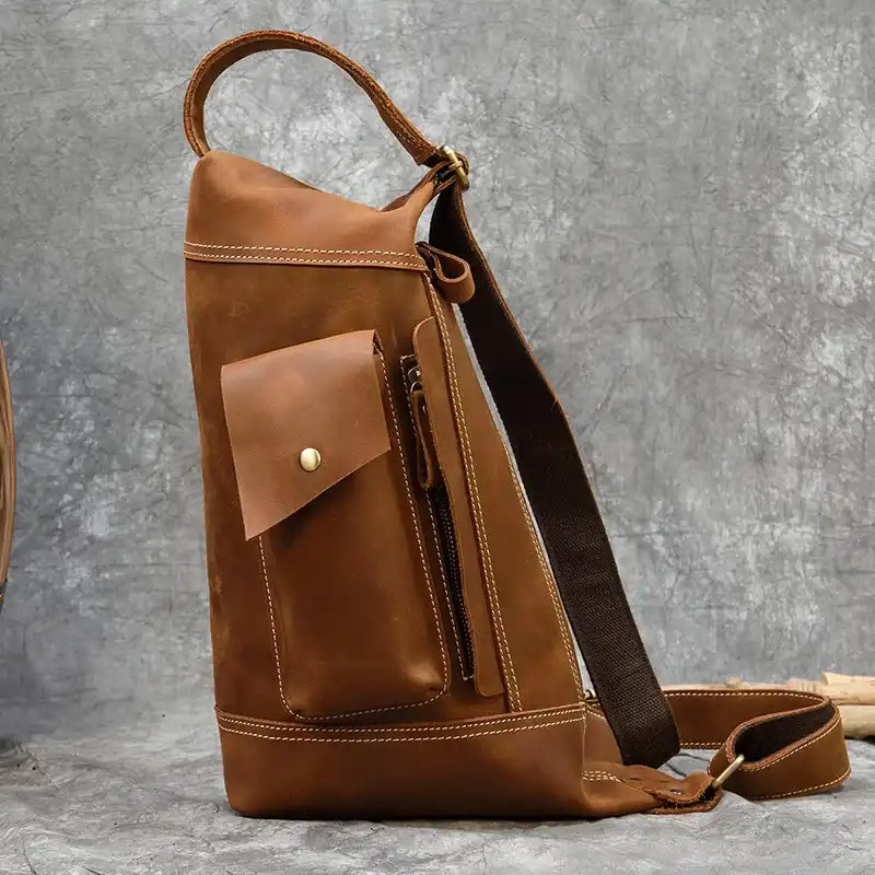 Side view of a vintage light brown leather bag with a pocket and zipper.