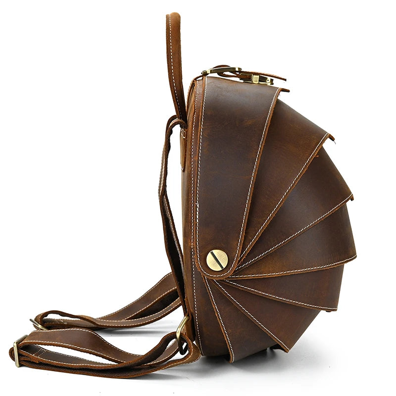 Brown leather backpack with distinctive fan-shaped design and straps - side view