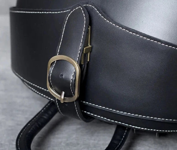Detail of a buckle on a black leather belt, highlighting the elegant finish and contrasting white stitching.