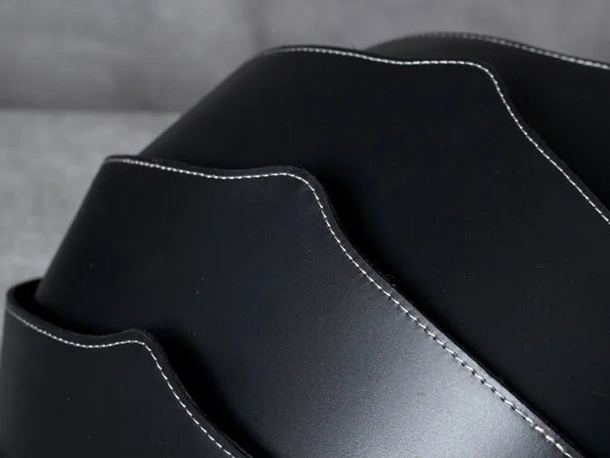 A wavy and elegant bag design in black leather, highlighting its white stitching and sophisticated texture.
